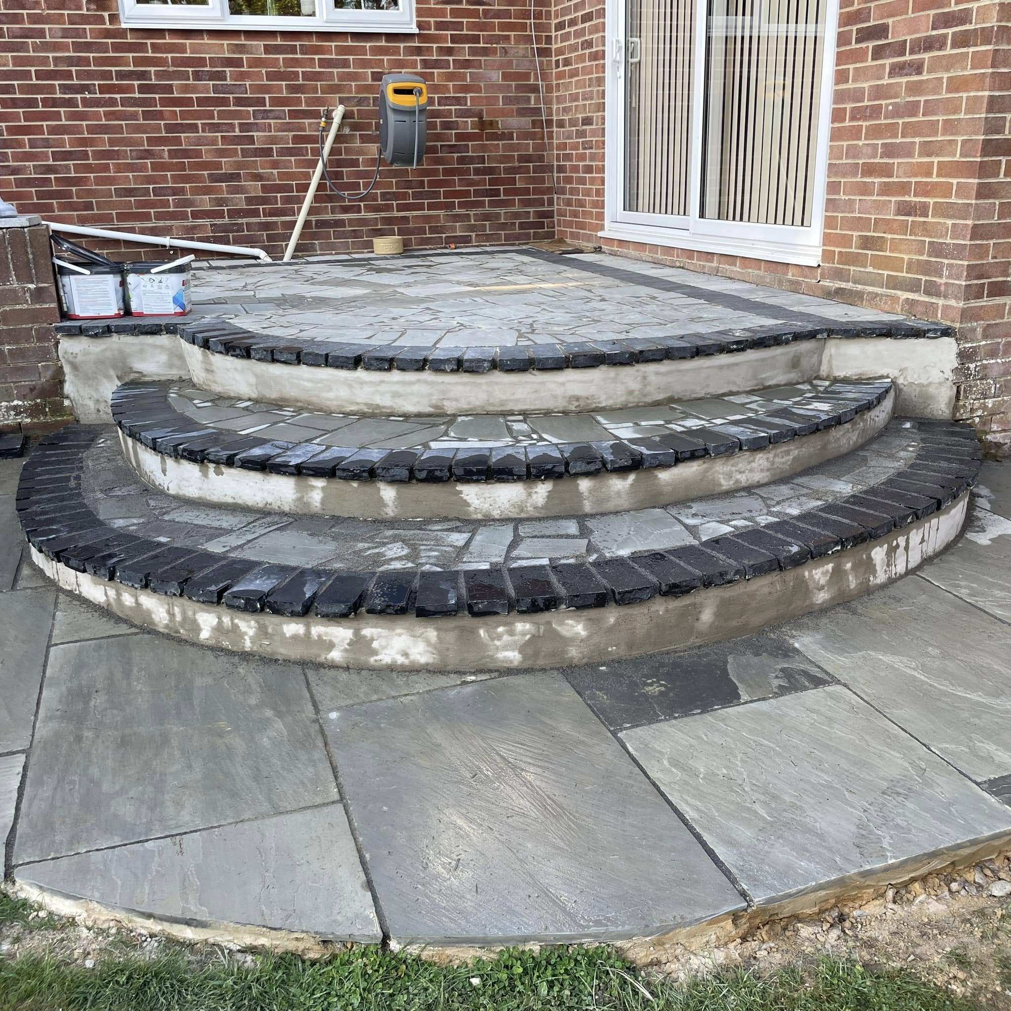 Stone patio with curved steps and brick edging